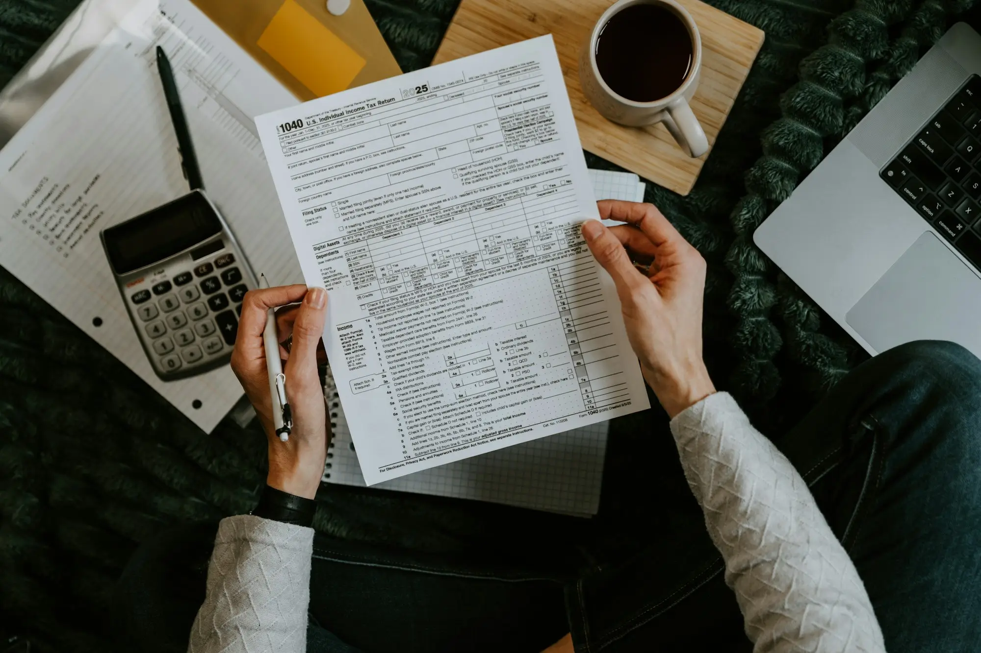 Tax paperwork, calculator and coffee on a home office desk