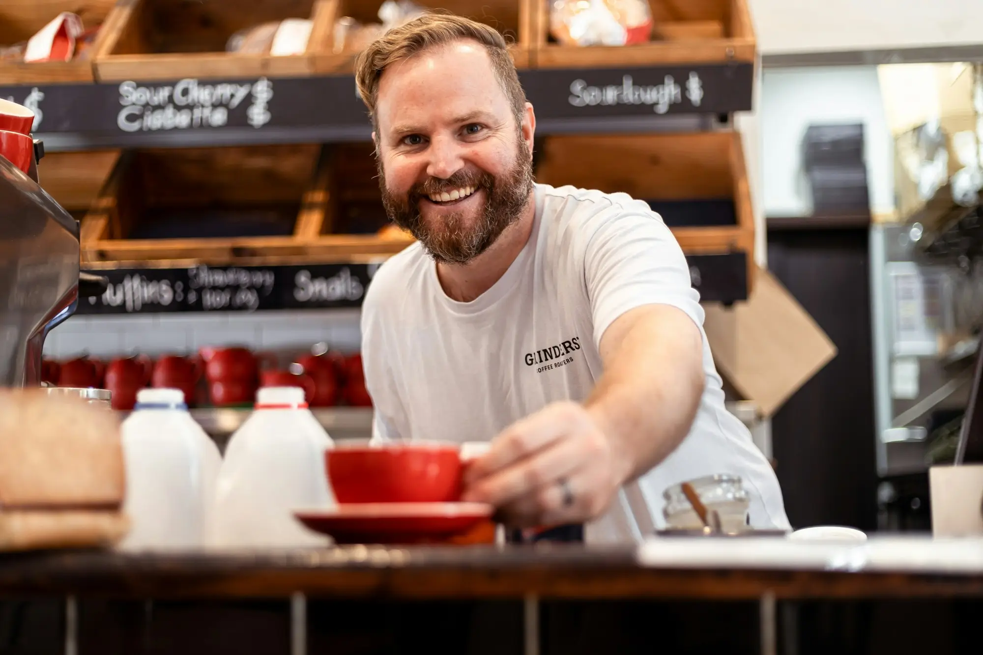 Smiling cafe owner serving coffee from behind the counter in Alexandria, Sydney